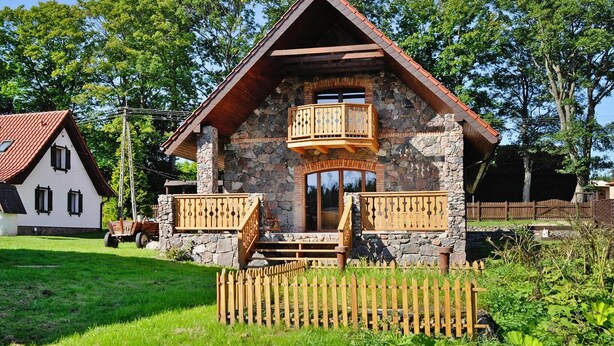 Une maison en pierre avec un balcon en bois et un toit rouge.