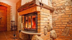 Une cheminée en pierre avec un feu de bois, une porte en bois et un sol carrelé.