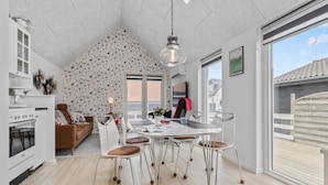 Una cocina moderna con área de comedor, que incluye una estufa blanca, un sofá marrón y una mesa de comedor con taburetes.