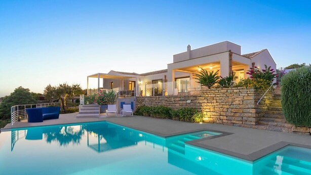 Ein modernes Haus mit Swimmingpool, Steinmauern und Sitzgelegenheiten im Freien.