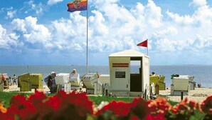 A beach with a flag, a lifeguard station, and beach chairs.