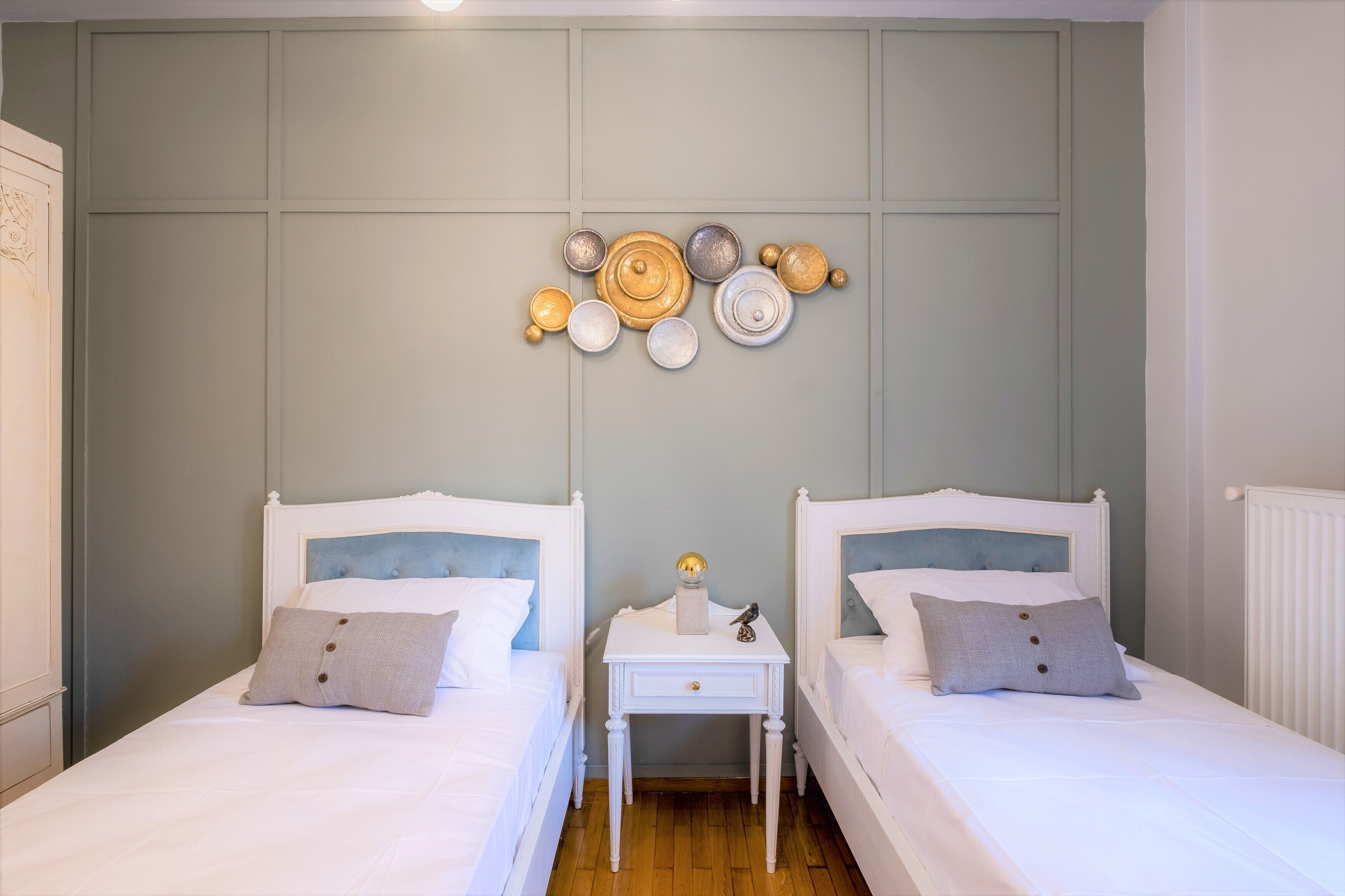 Une chambre avec deux lits simples, une petite table de chevet et un élément décoratif mural.