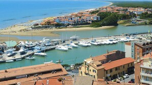 A coastal town with a marina, buildings with red-tiled roofs, and a beach in the background. - Apartment near Grosseto beaches and pine forest (Marina di Grosseto)