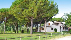 A white villa with a fenced yard, surrounded by tall pine trees. - Apartment near Grosseto beaches and pine forest (Marina di Grosseto)