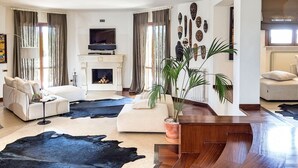 A modern living room with a fireplace, two sofas, a coffee table, and a large potted plant.