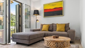 A modern living room with a grey sectional sofa, two mustard-colored cushions, a wooden coffee table, and a floor lamp. - Classic Urban Flat in Malaga City Center - Mal05 (Málaga)