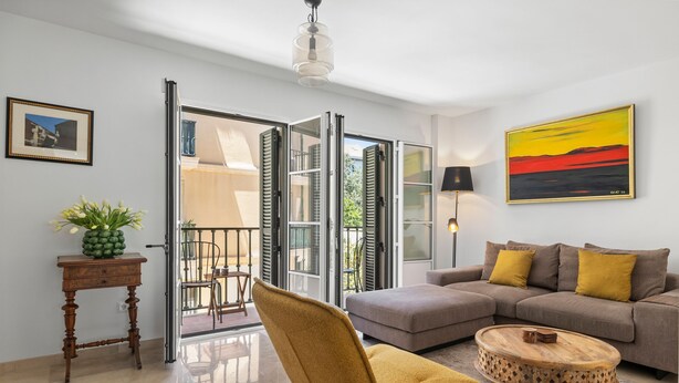 A modern living room with a sofa, a round coffee table, a chair, a small table with a plant, and a painting on the wall. - Classic Urban Flat in Malaga City Center - Mal05 (Málaga)