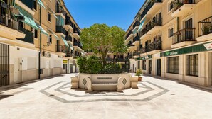A courtyard with a central planter, surrounded by multi-story buildings with balconies and air conditioning units. - Classic Urban Flat in Malaga City Center - Mal05 (Málaga)