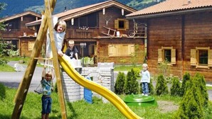 Una baita di legno con uno scivolo giallo in un'area erbosa.