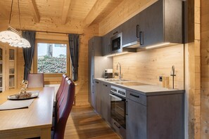 A modern kitchen with wooden cabinetry, a built-in oven, and a large window.