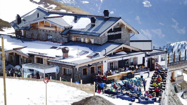 Un hotel con facciata in pietra, diverse finestre e tetto innevato.