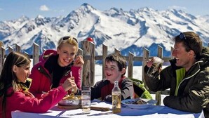 Un gruppo di persone che cena a un tavolo con le montagne sullo sfondo.