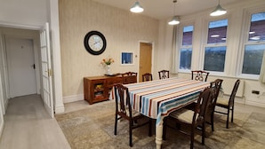 A dining area with a wooden table, chairs, a clock, and a window with curtains. - Blue Vista (Bournemouth)