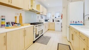 A modern kitchen with light-colored cabinets, a stove, microwave, and refrigerator. - Blue Vista (Bournemouth)