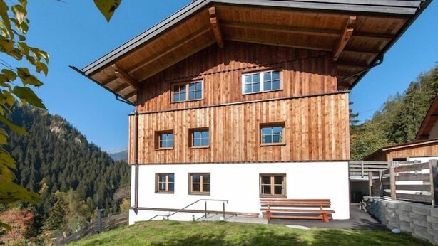 Un chalet en bois doté d’un toit à pente, de nombreuses fenêtres et d’une partie inférieure peinte en blanc.