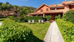 Un edificio residencial con un sendero jardín, mobiliario exterior y un paisaje de colinas.