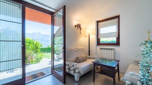 Una habitación con sofá, una mesita, una lámpara y vistas a la montaña a través de un ventanal corredero.