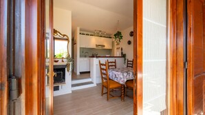 Un comedor con una mesa y sillas, una cocina al fondo y un marco de puerta de madera.