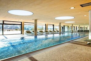 Relax by the pool with a view of the surrounding landscape, surrounded by lounge chairs and under a contemporary ceiling design.