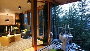 Ein gemütliches Wohnzimmer mit einer Couch, einem Esstisch und einem Balkon mit Tisch und Stühlen.