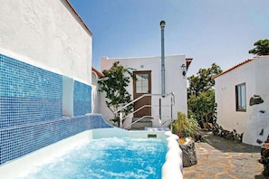 A spa area with a hot tub, stone pathway, and white buildings with blue-tiled walls.