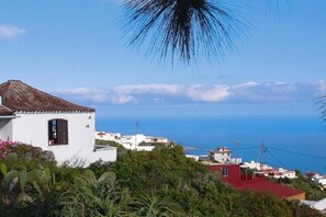 Un pueblo costero con edificios blancos, una construcción de techo rojo y vista al mar.