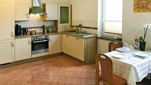 Eine kompakte Küche mit Einbauofen, Kaffeemaschine und einer Essecke mit Tisch für zwei Personen.