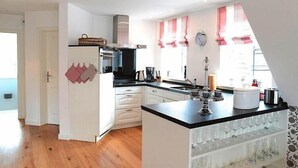 A kitchen with white cabinets, a black countertop, and a glass wine rack.