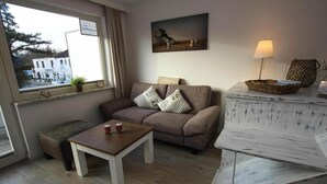 Un salon chaleureux avec un canapé, une petite table sur laquelle reposent deux tasses, une lampe et un tableau accroché au mur.