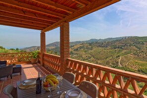 A terrace with a table set for dining, overlooking a hilly landscape. - Villa Castillo in Frigiliana (Frigiliana)