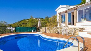 Une piscine avec un mur en pierre et un bâtiment blanc en arrière-plan.