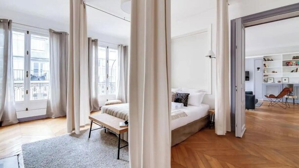 Une chambre moderne avec un lit, une table de chevet et une vue sur un balcon.