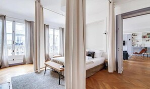Quarto moderno com cama, mesa de cabeceira e vista para uma varanda.