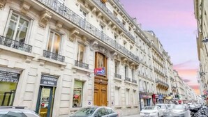 Un immeuble à plusieurs étages, de style architectural classique, caractérisé par des balcons richement décorés et de grandes fenêtres.