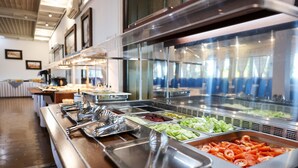 Een buffet met diverse gerechtjes, waaronder groenten en vlees, gepresenteerd op metalen schalen.