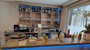 A bar area with shelves of liquor bottles, glasses, and a VELTINS beer tap. - PB Hotel Pension (Goslar)