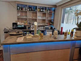 Zona de bar con estanterías llenas de botellas de licores, vasos y una grifo de cerveza VELTINS.