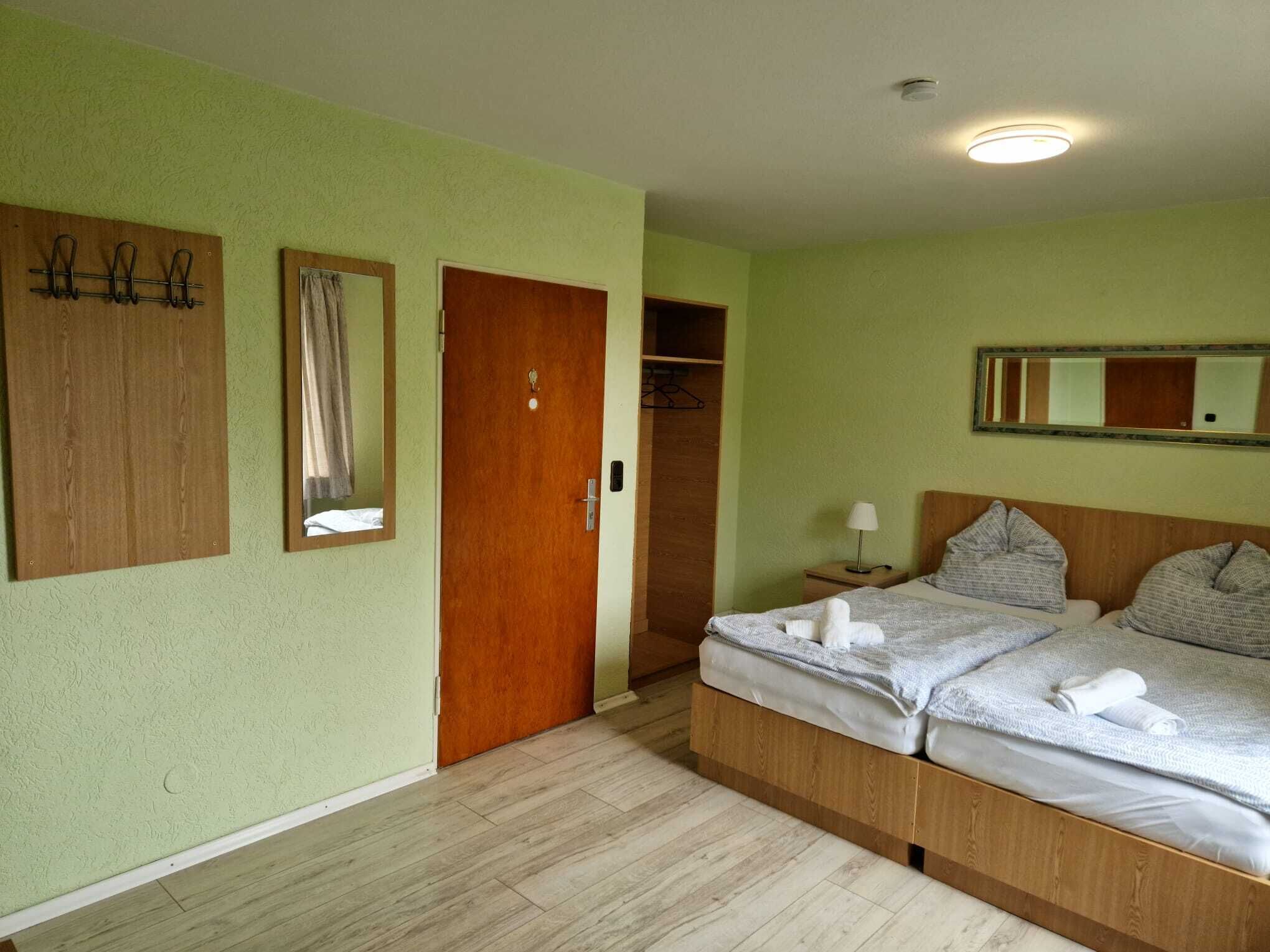 Une chambre à coucher avec un lit, une armoire en bois, un miroir et une porte.