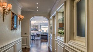 A hallway with a wooden floor, white walls, and a large arched doorway leading to a living area with furniture and a view of the cityscape. - 
Luxurious Apartment Overlooking the Colosseum  (Roma)