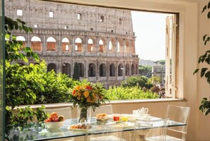 A dining table with a view of the Colosseum, clear glass chairs, and a vase of flowers. - 
Luxurious Apartment Overlooking the Colosseum  (Roma)