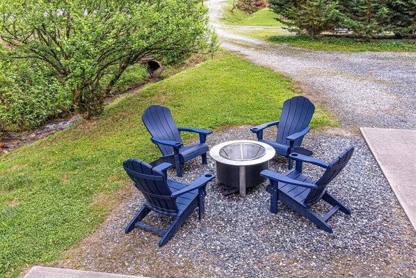 A patio with four Adirondack chairs and a circular fire pit. - Escape to the serene Diamond Creek Cabin (Bryson City)