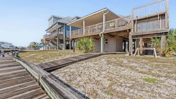 Une propriété située en bord de mer, dotée d’une terrasse en bois, de plusieurs balcons et d’une plage de sable.