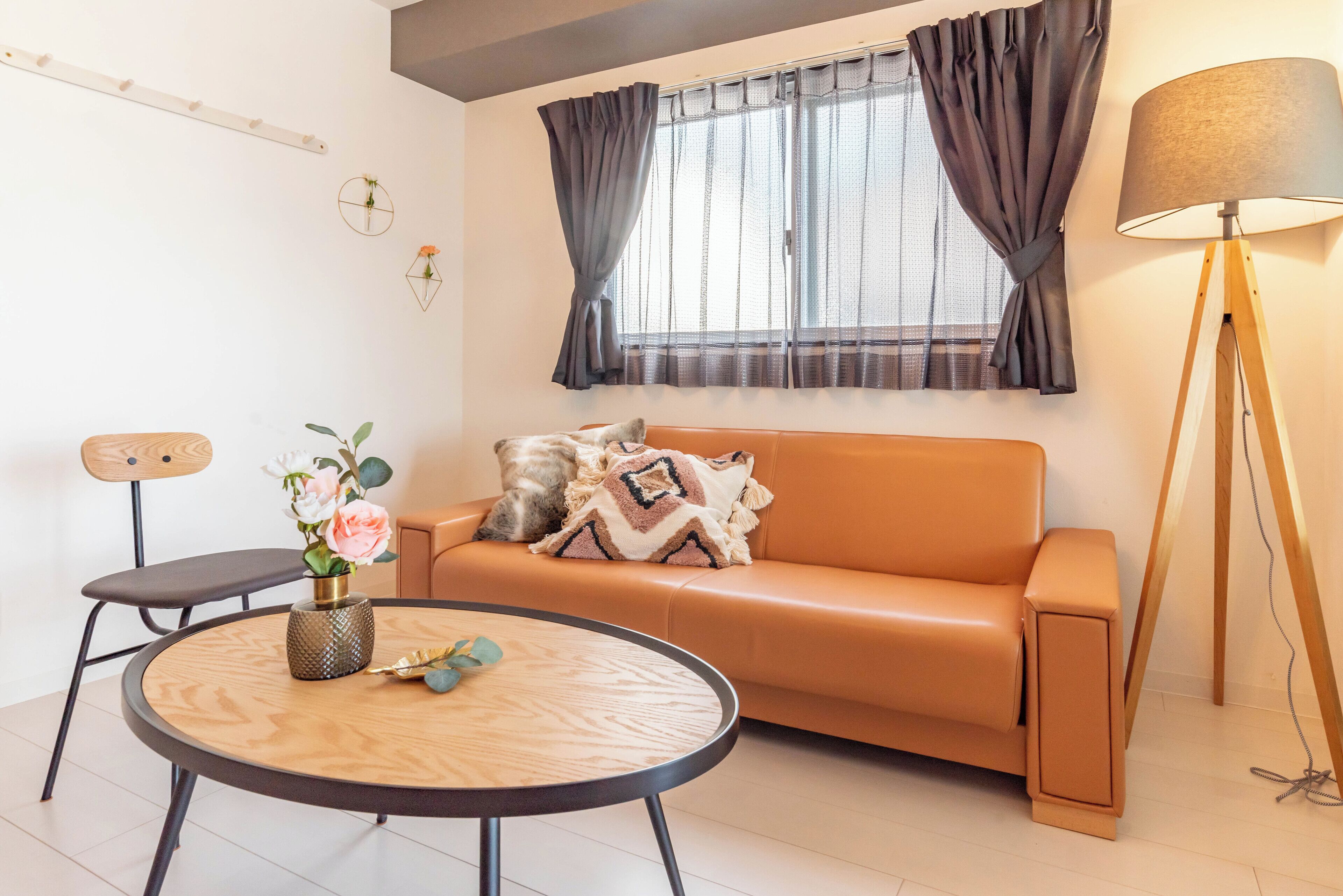 A modern living room with a sofa, a round wooden table, and a floor lamp.