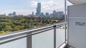 A city skyline with modern buildings, a green sign, and a balcony railing. - Bijou Suites Bloom (Osaka)
