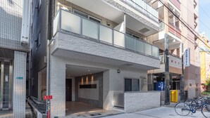 A modern building with a glass balcony, a visible entrance, and a bike parking area. - Bijou Suites Bloom (Osaka)
