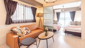 A modern hotel room with a sofa, a small table, a lamp, and a bed. - Bijou Suites Bloom (Osaka)