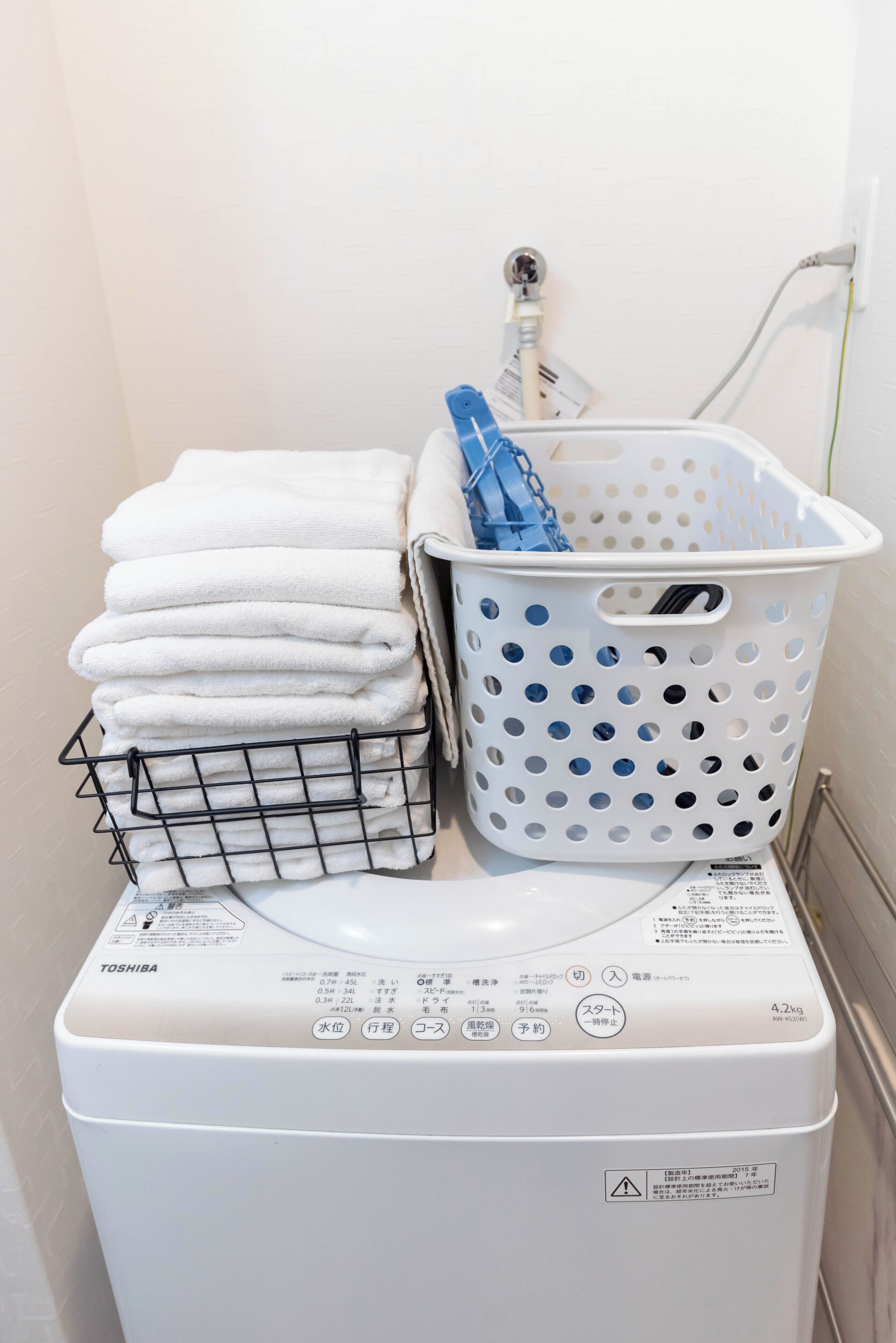A washing machine with a white basket and towels on top.