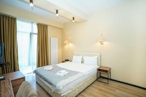 Una habitación de hotel con una cama, mesitas de noche, un escritorio y un televisor.