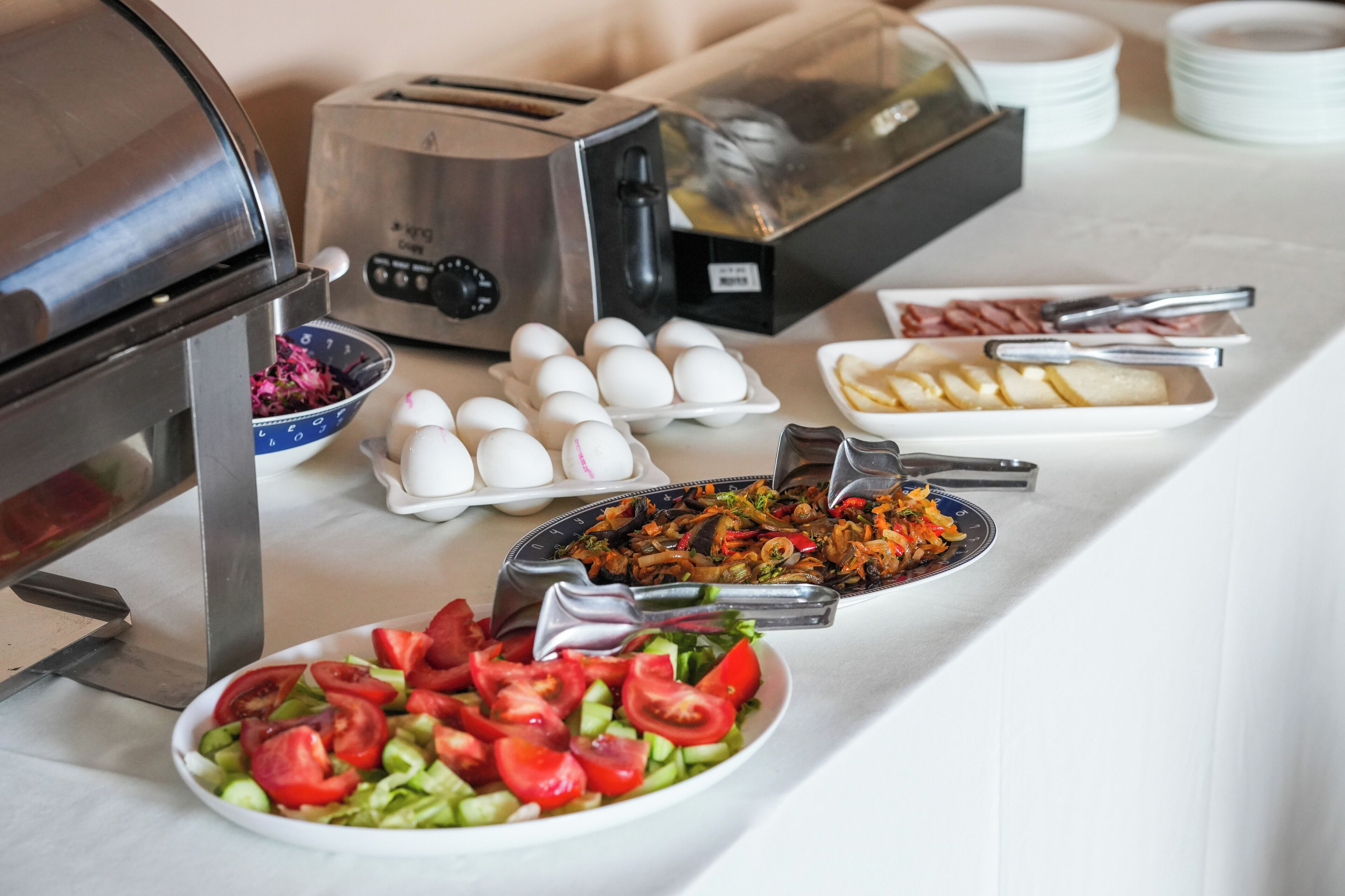 Une table de buffet proposant divers plats, notamment des œufs, du pain tranché et une salade.