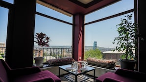 A balcony with a glass table, purple chairs, and potted plants. - Andza Tbilisi Hotel (Tbilisi)
